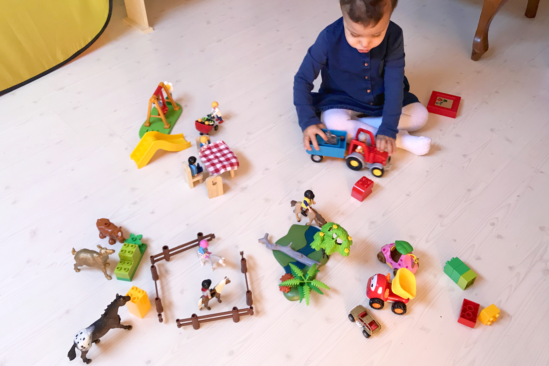Bébé jouant avec ses personnages et animaux Playmobil et Duplo