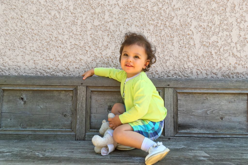 Petite fille et son doudou Moulin Roty. Gilet Petit Bateau. Chaussures Verbaudet