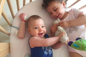 Bébé et sa grande soeur riant avec leur doudous Moulin Roty
