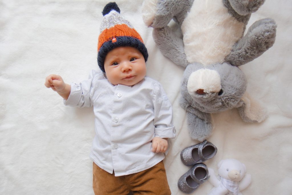 Bébé dans un pantalon Petit Bateau, bonnet Oabïdi et chaussures Sergent Major. Doudou
