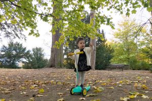 Enfant sur une trotinette au parc de Beauregard en automne