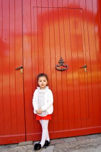 Petite fille devant une porte rouge