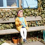Petite fille sur un banc, mange son gâteau, dans un village en pierre