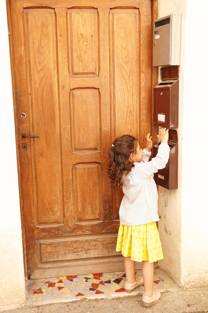 Petite fille joue avec une boîte aux lettres